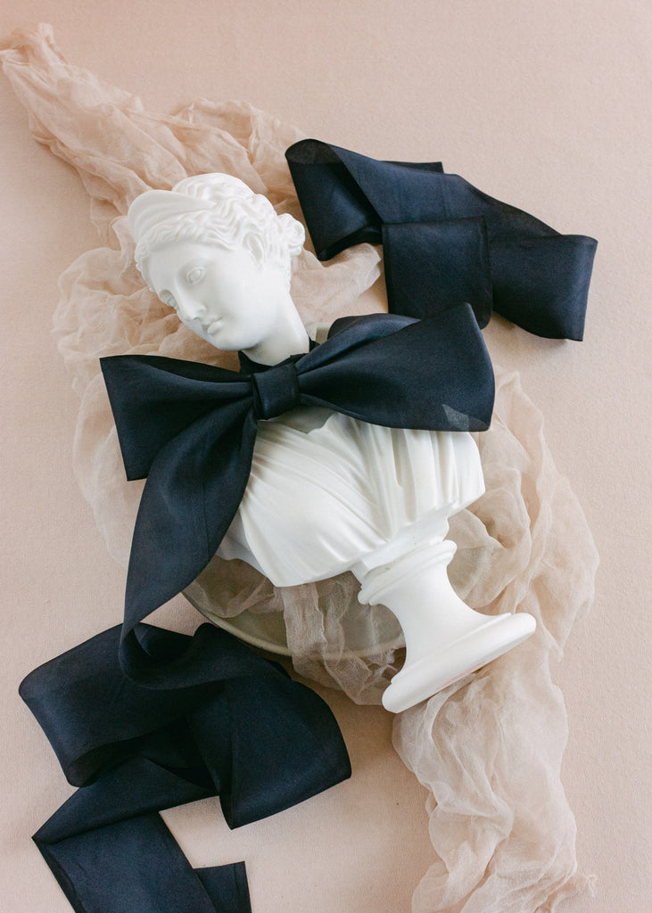 White sculptural bust tied with 2.5 inch wide, hand-dyed black silk ribbon, styled with romantic draping fabric accents.