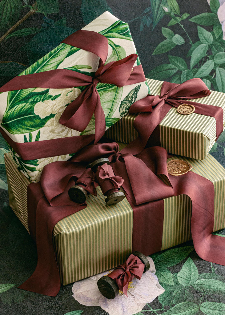 Elegant rolls of luxury burgundy silk ribbon with rich maroon hues, arranged for holiday wrapping inspiration