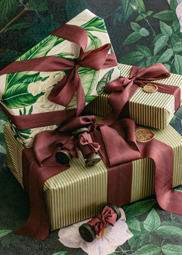 Elegant rolls of luxury burgundy silk ribbon with rich maroon hues, arranged for holiday wrapping inspiration