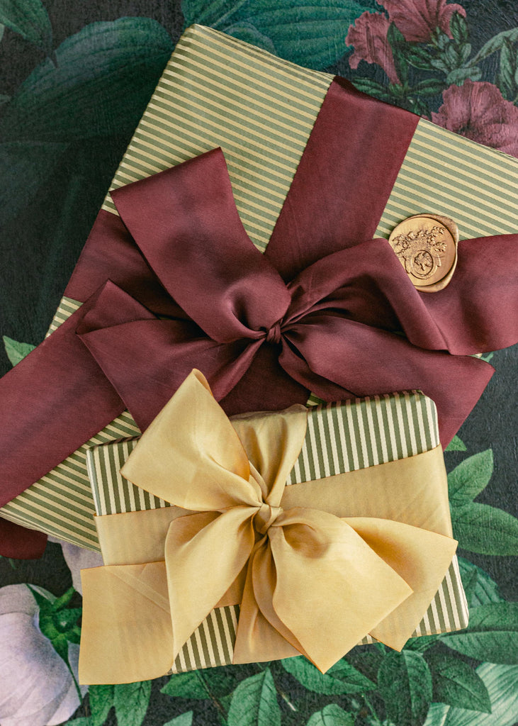 hand-dyed maroon silk ribbon and gold silk ribbon tied around a christmas gifts with big bows