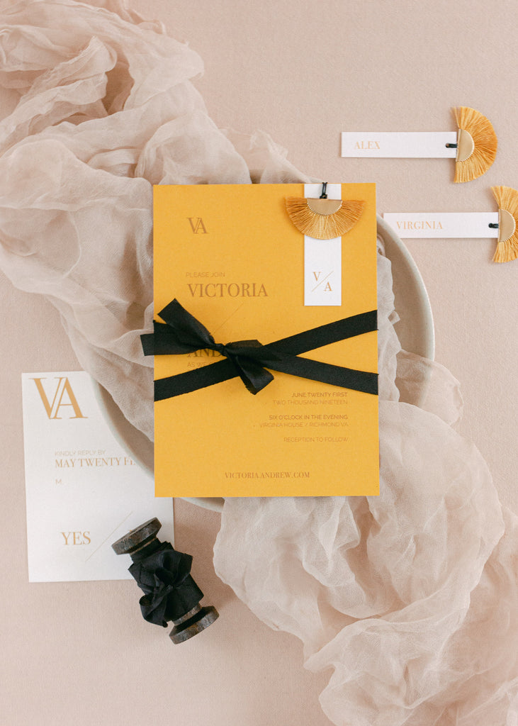 Hand-dyed black silk ribbon used as an accent on wedding stationery, adding a refined and romantic touch against soft neutral textures