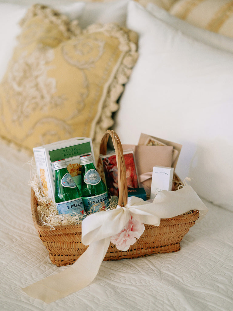Soft white silk ribbon tied in a bow around a wedding guest welcome basket, also perfect for invitations and event details