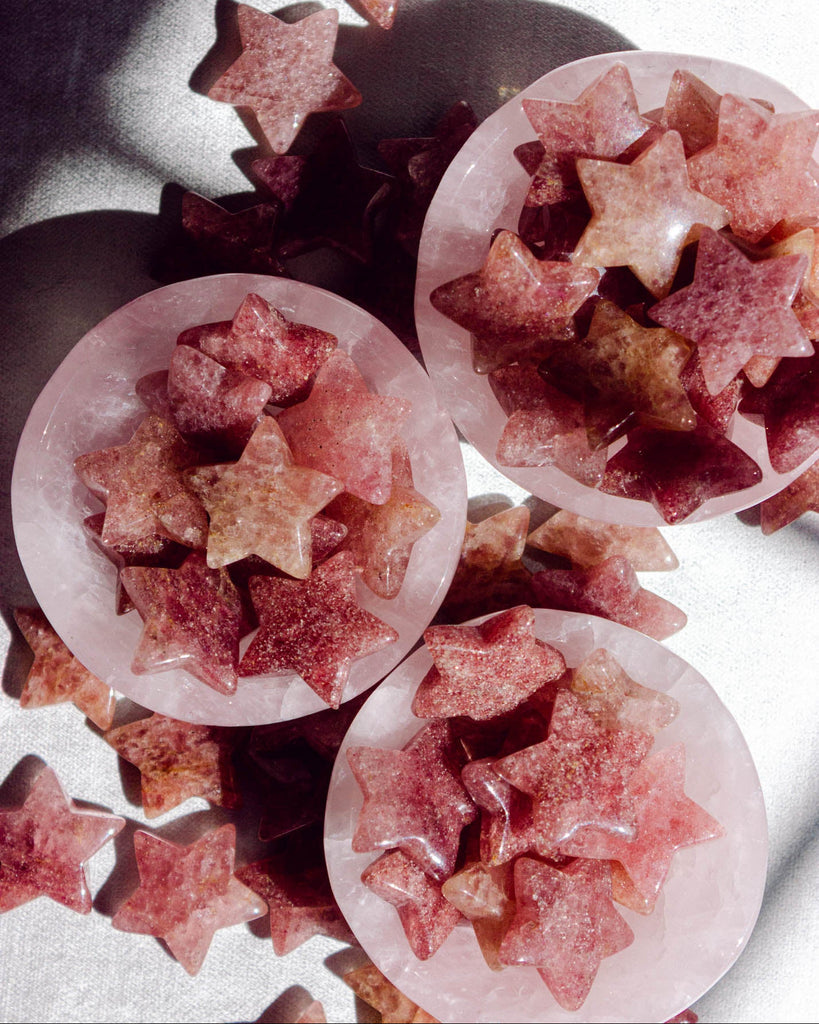 Cluster of natural strawberry quartz stars with sparkling tones of pink, mauve, and soft red.