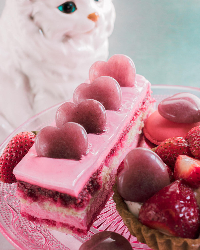 Polished heart-shaped natural Strawberry Quartz crystal resting on cake, showing its soft red and translucent streaks.