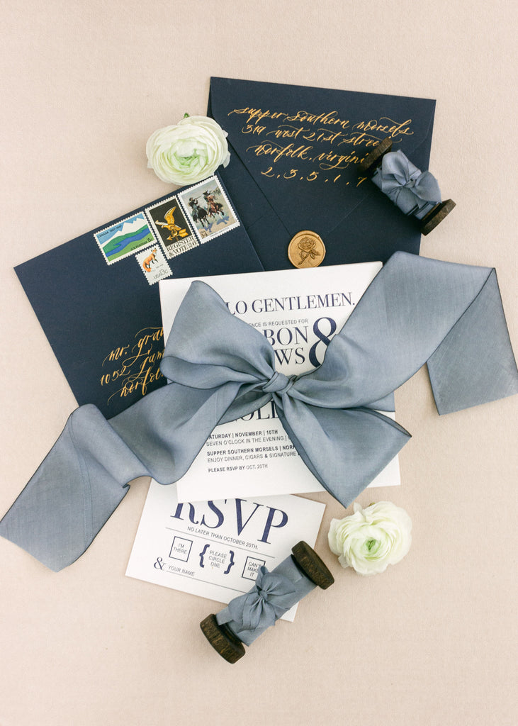 Dusty blue silk ribbon wrapped around wedding stationery, adding a romantic finishing touch to the invitation suite