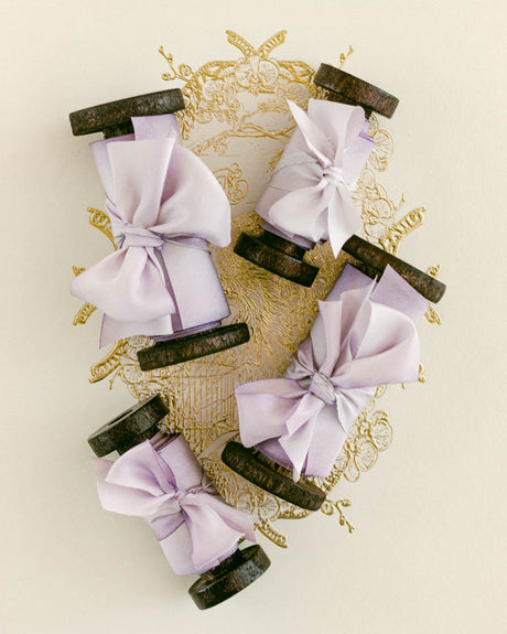 Hand-dyed lavender silk ribbon on dark vintage-style wood spools with soft bows and flowing silk.