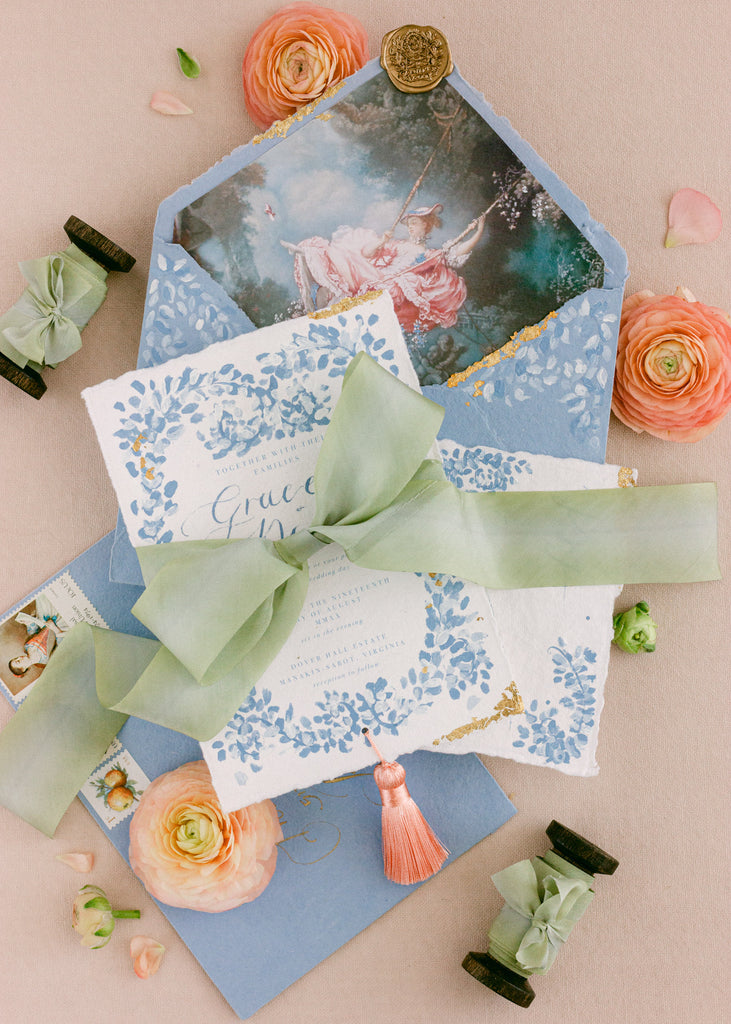 Luxury sage green silk ribbon tied around a wedding invitation suite, a hand-dyed ribbon detail for modern weddings