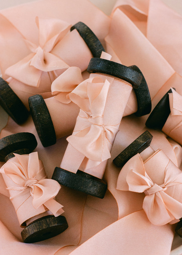 hand dyed peach ribbon on dark wood spool
