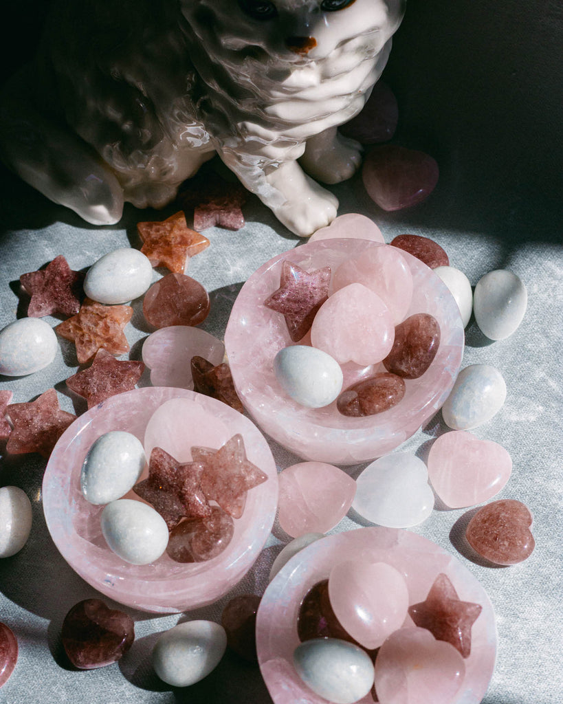 Rose quartz crystal bowls with star-shaped  strawberry quartz crystals on velvet surface