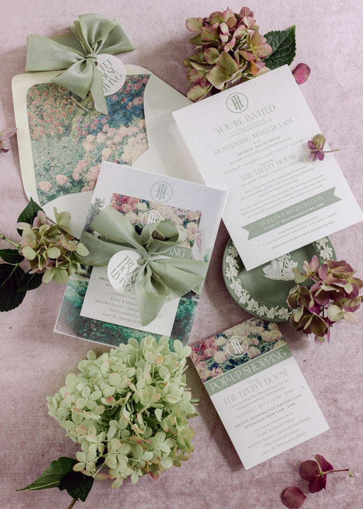 Soft sage green silk ribbon tied in a bow around a wedding invite, adding a luxury touch to bridal stationery