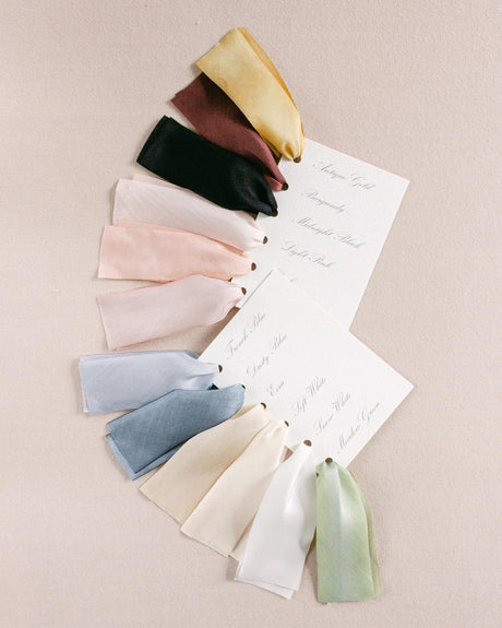 Assorted hand-dyed silk ribbons samples in multiple shades, fanned out to showcase color variations and artisanal quality.
