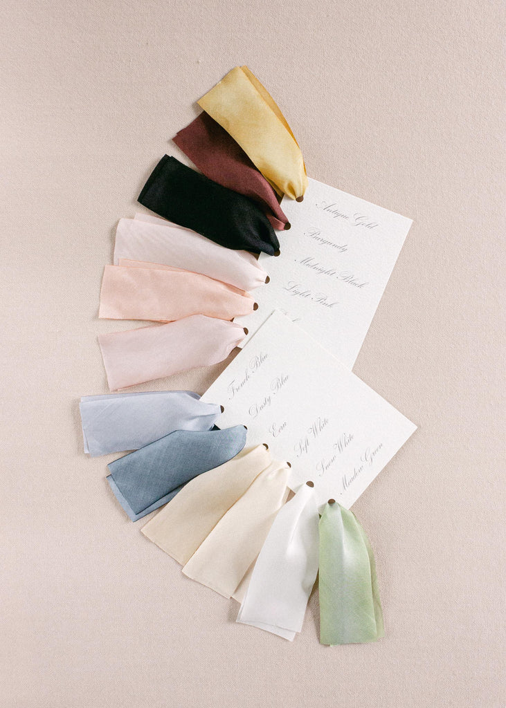 Assorted hand-dyed silk ribbons samples in multiple shades, fanned out to showcase color variations and artisanal quality.