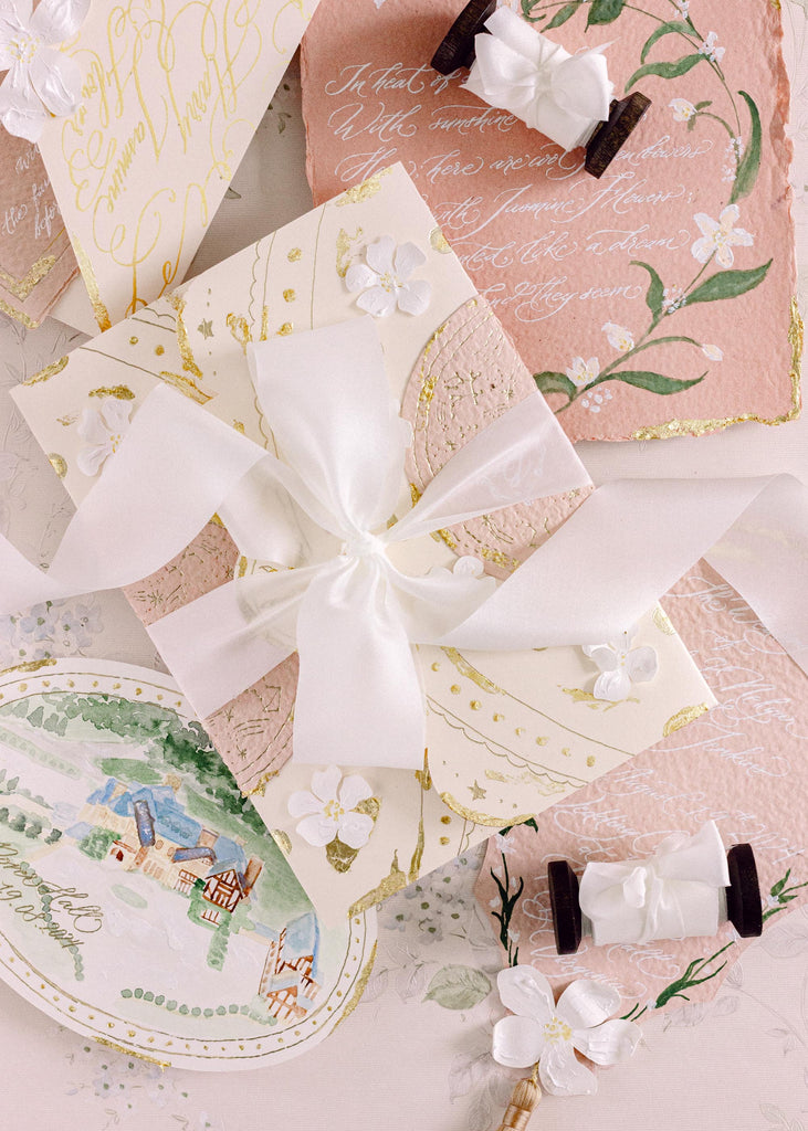 luxury bias cut white silk ribbon tied in a bow around hand made wedding invitations
