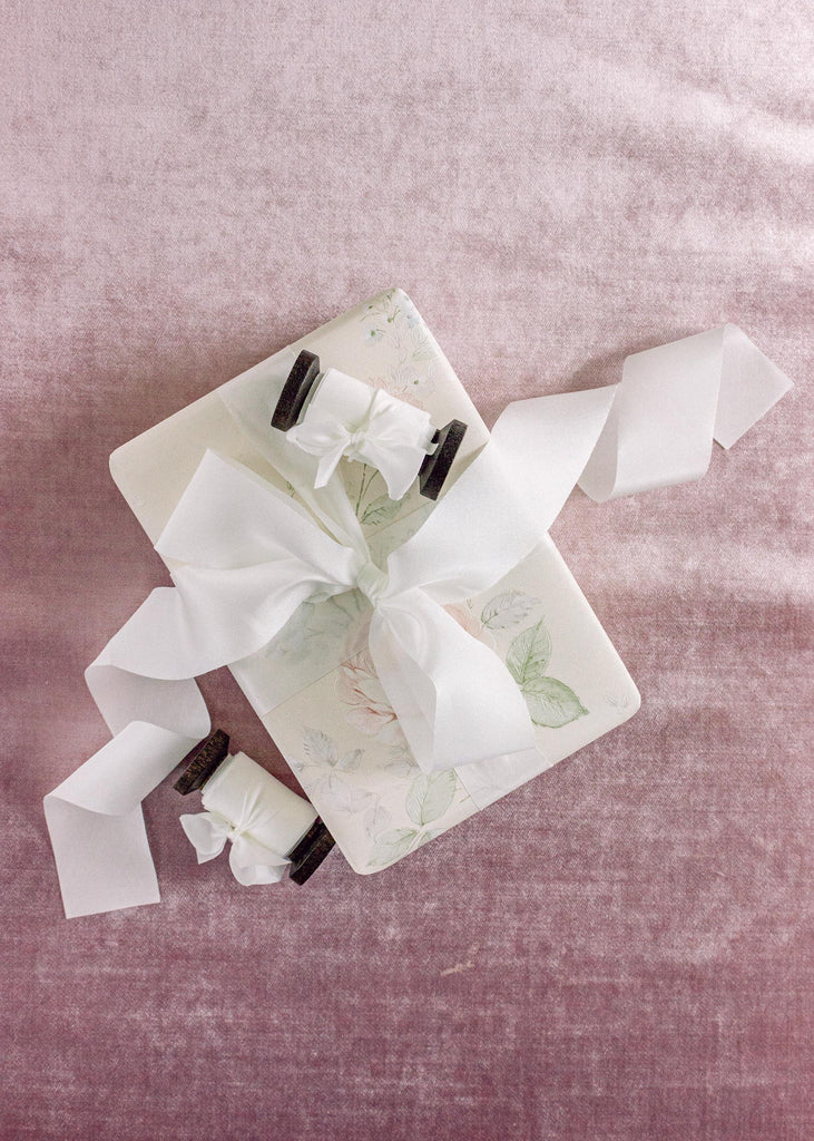 white silk ribbon tied around a wedding gift on a velvet background.
