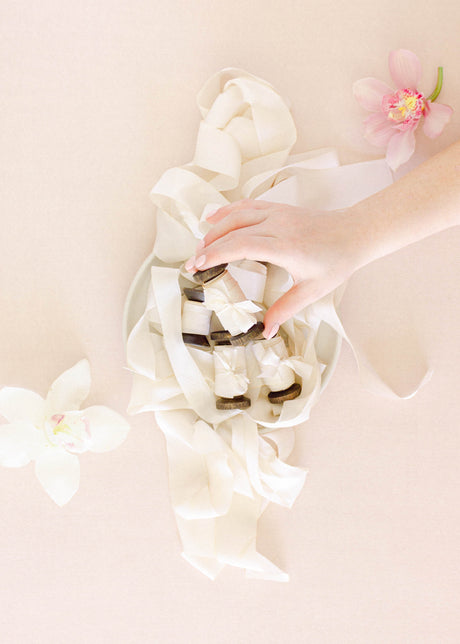 Hand dyed soft white silk ribbon rolled on a wooden spool, perfect for wedding invitations, gift wrapping, and bouquet accents