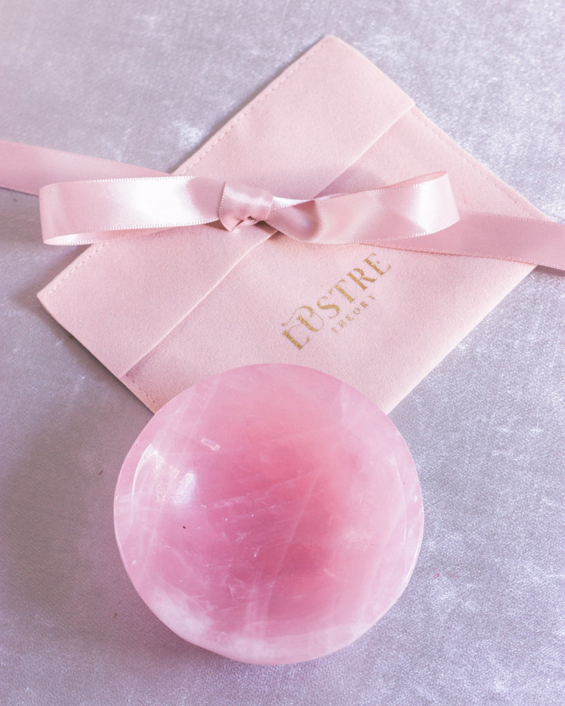 pink rose crystal bowl for jewelry next to a gift pouch.