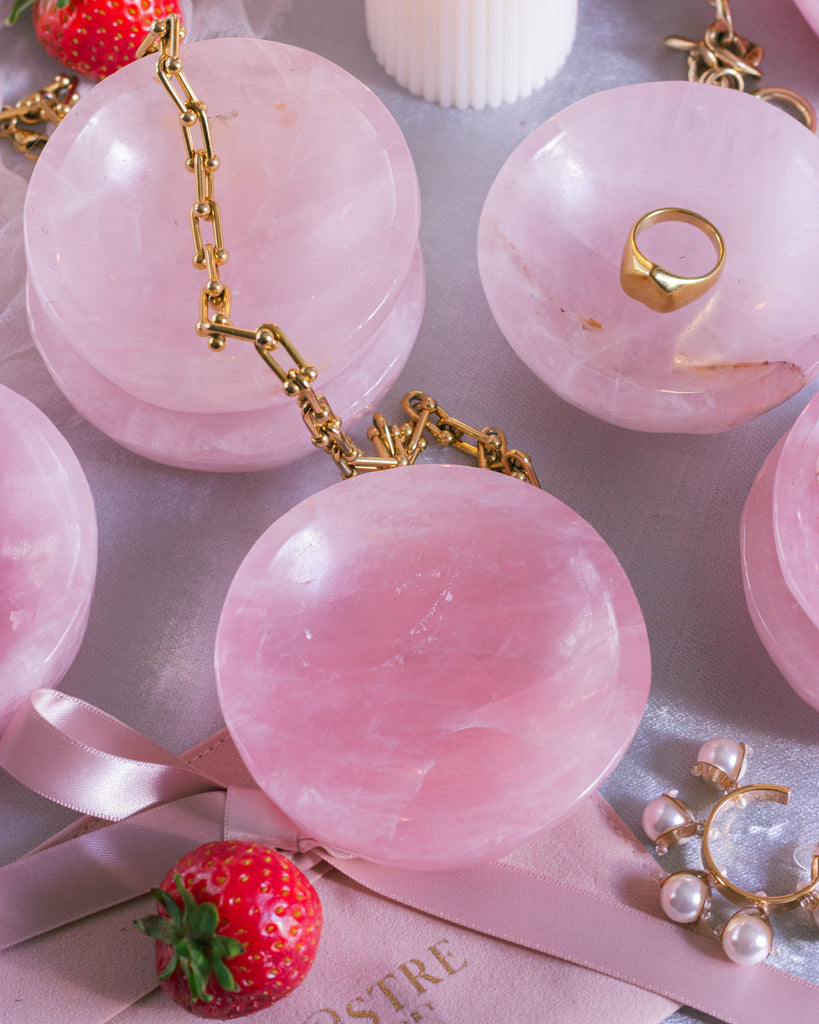 Top-down view of a hand-carved Rose Quartz crystal dishes, showing smooth curves and natural inclusions, styled with heart chakra crystals on a velvet surface.