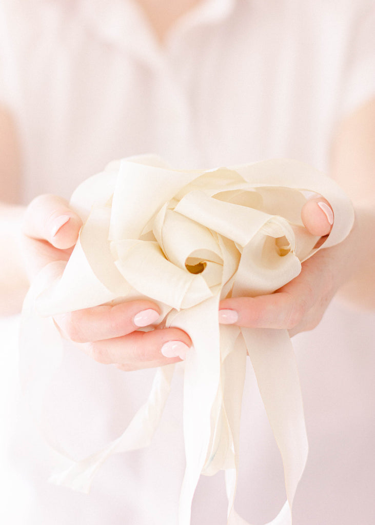 a pile of elegant hand dyed soft white silk ribbon for bouquets, invitations, and wedding décor accents