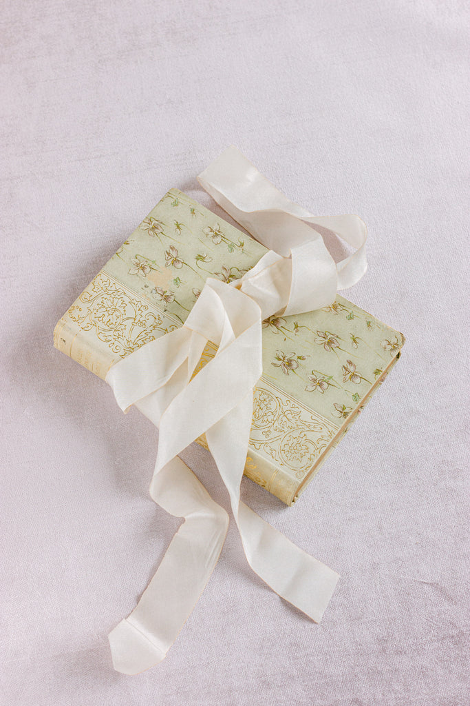 Luxury soft white silk ribbon displayed alongside wedding invitations and bouquets, highlighting its hand dyed texture